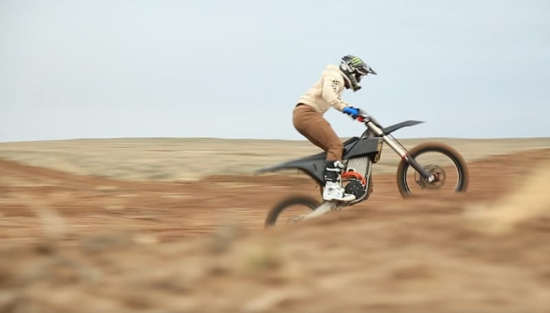 A person riding the Model-1 Prototype Motorbike at high speed across a barren landscape, captured in motion blur.