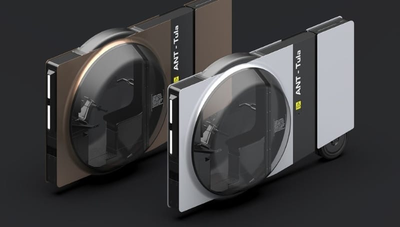 Two futuristic, enclosed, single-seat personal transport vehicles with a circular, transparent front window. One vehicle is brown, labeled "ANT - Tula," the other is silver, labeled "ANT.