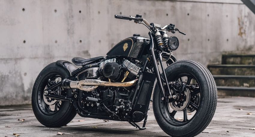 Custom black motorcycle parked on a concrete surface with a minimalist urban background.