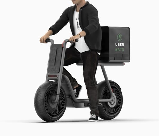 A man riding a scooter with a 2019 concept box on it.