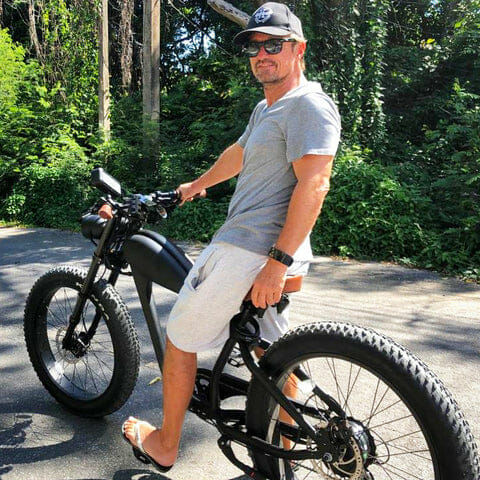 A man is posing on a bike in the woods.