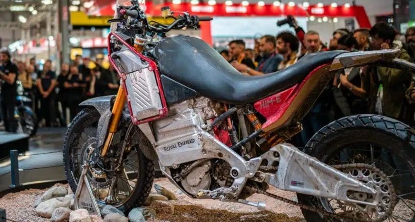A Royal Enfield Himalayan motorcycle displayed on a rocky platform surrounded by spectators at an exhibition.