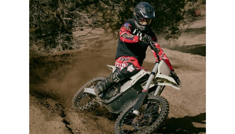 A motorcyclist in red and black gear rides the Model-1 Prototype Motorbike, kicking up dust on a rugged trail.