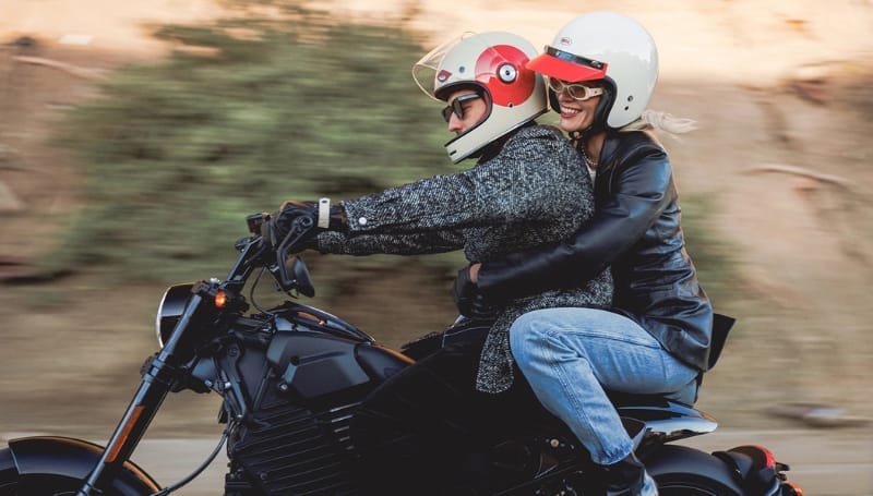 Two people wearing helmets riding a motorcycle.