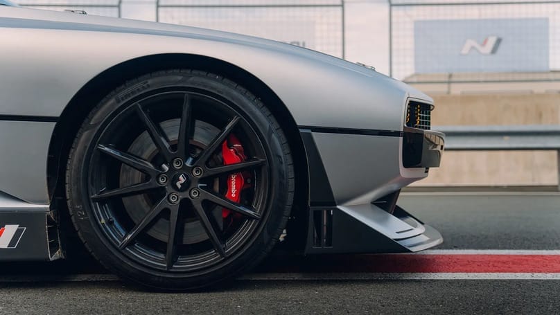 A close up of a silver sports car with red wheels.