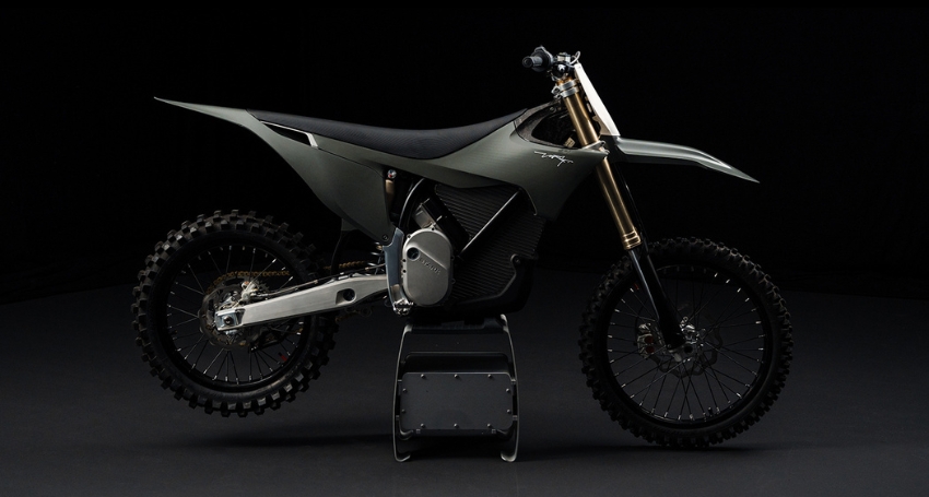A sleek, modern dirt bike with a matte black and metallic design is displayed on a stand against a dark background.