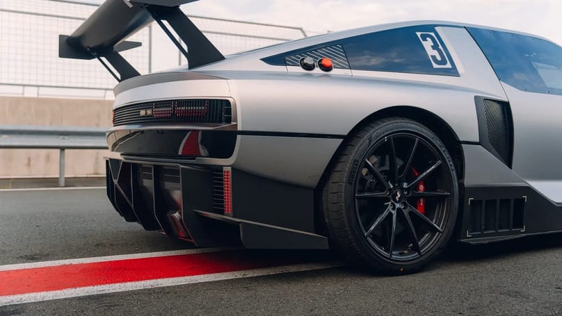 A silver sports car is parked on a track.