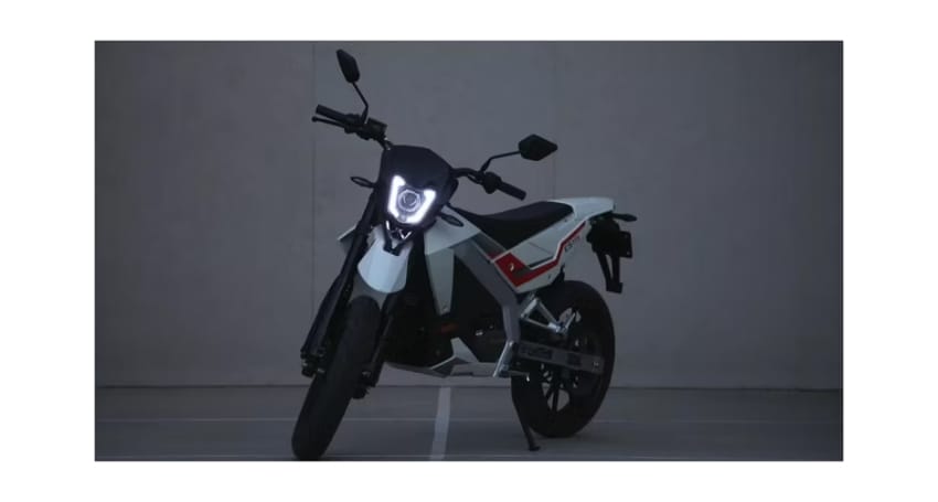 A white and black motorcycle is parked in a gray room.