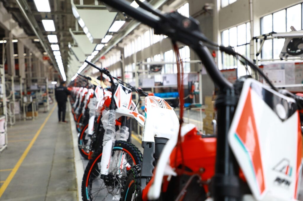 A line of dirt bikes in a factory featuring Apollo's RFN Electric Motorbike Upgrades.