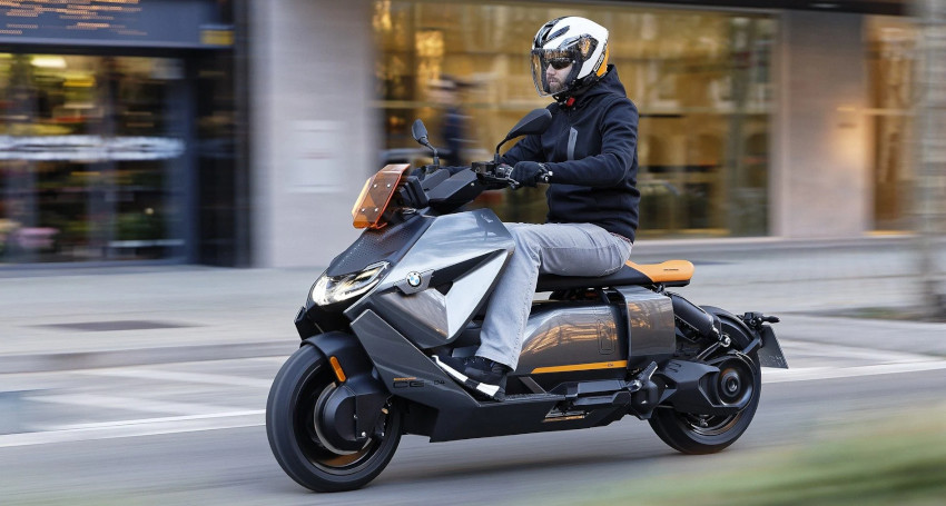 A person wearing a helmet and dark clothing rides a modern <a href=