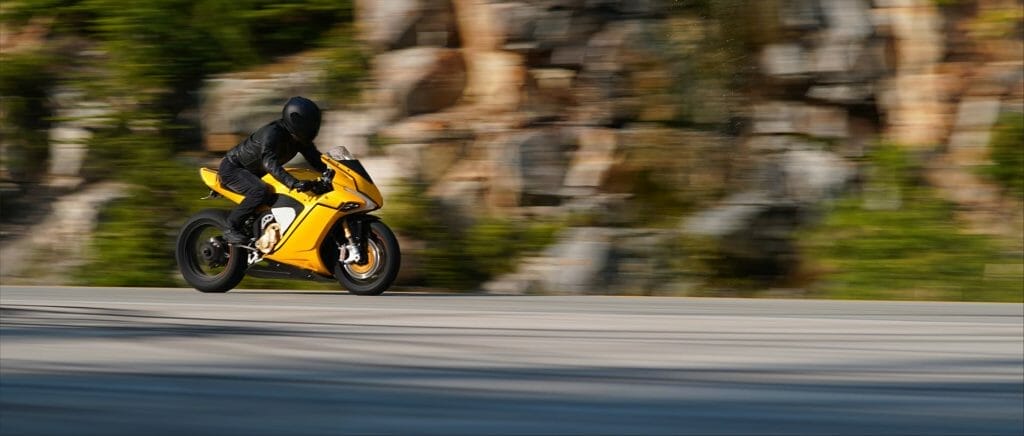 a man wearing a helmet riding a motorcycle down a street