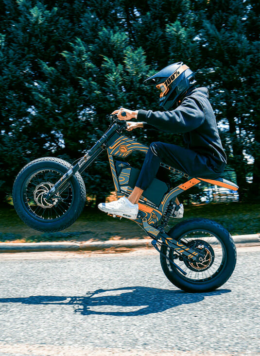A person performing a stunt on a ERoybikes motorcycle with powerful hub motors.