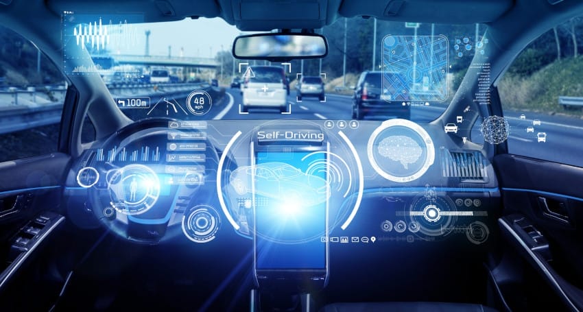 Interior of a self-driving car with a digital interface displaying various driving and navigation information while traveling on a highway.