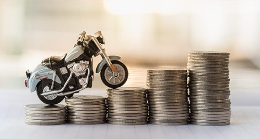 A miniature electric motorbike is placed atop a rising stack of coins, symbolizing financial growth and investment.