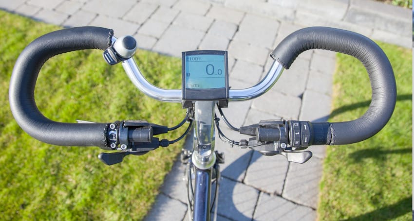 Close-up view from a cyclist's perspective looking down at the handlebars and electronic display of the best e-bike for your lifestyle, showing 0.0 on the display.