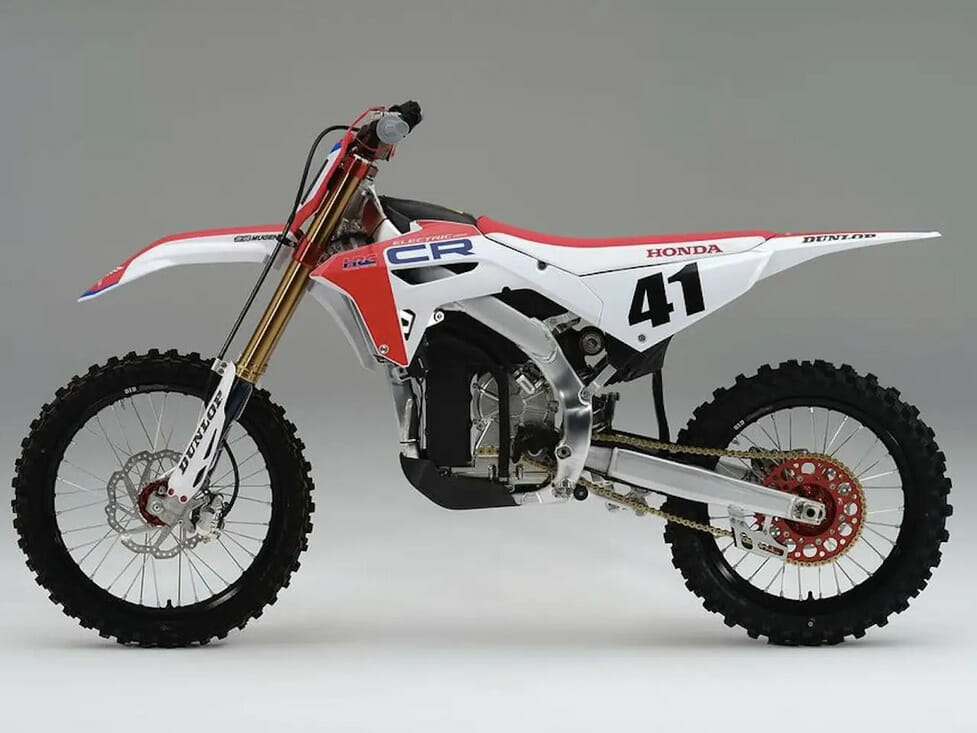 A red and white dirt bike sits on a gray background at Honda's CR ELECTRIC PROTO Debut.
