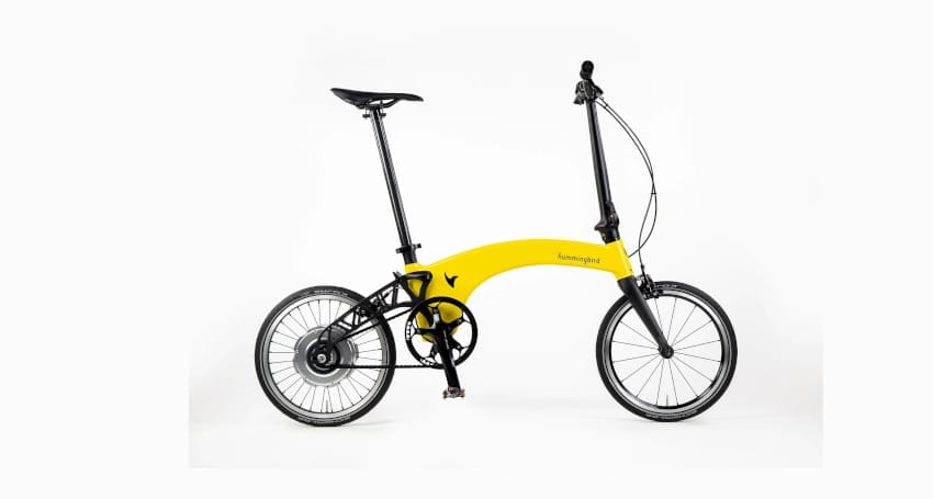 A yellow folding Hummingbird Electric 2.0 bicycle with a black seat and black handlebars, designed for urban commuting, this model incorporates features of the lightest electric bike to ensure effortless rides.