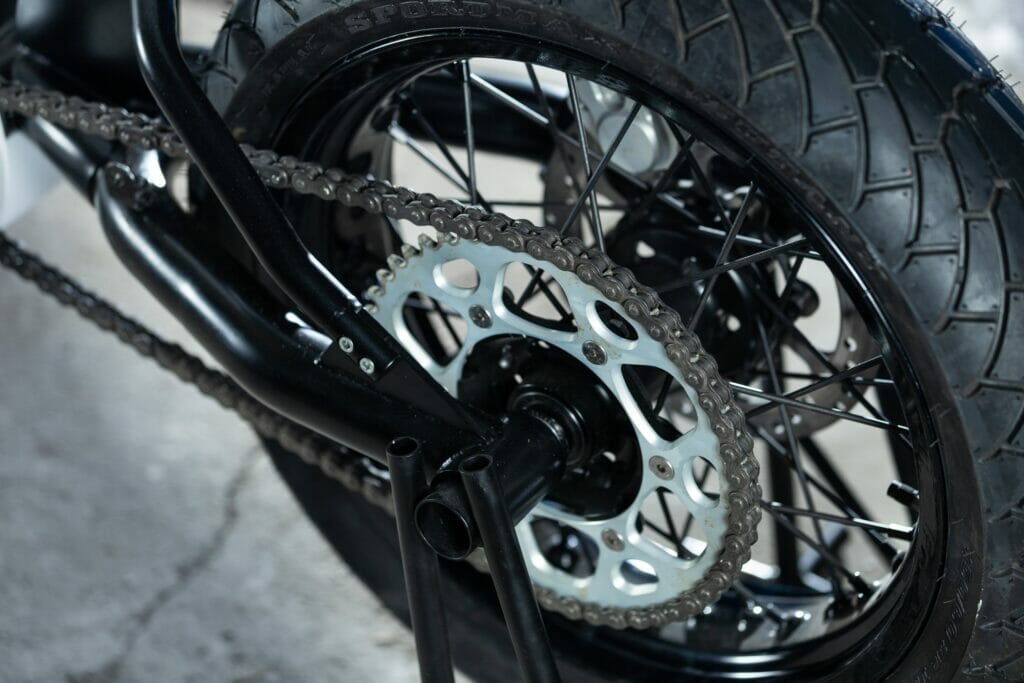 A close up of the Death To Petrol motorcycle wheel and chain.
