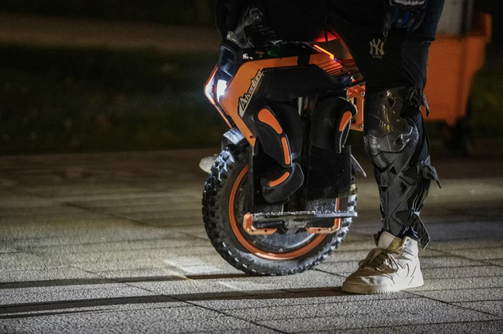 A powerful InMotion Adventure Unicycle rider balances skillfully on their off-roading beast under the night sky.