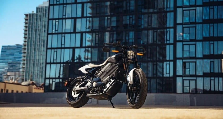 A motorcycle parked in front of modern glass buildings.