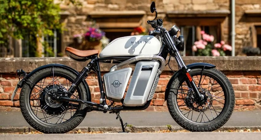 A white Makking electric motorbike with a vintage design is parked on a street in front of a brick wall, showcasing the charm of electric motorbikes in Europe.