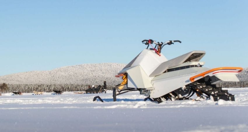 An electric snowmobile is parked in the snow.