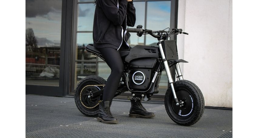 A woman is standing on a black electric bike.