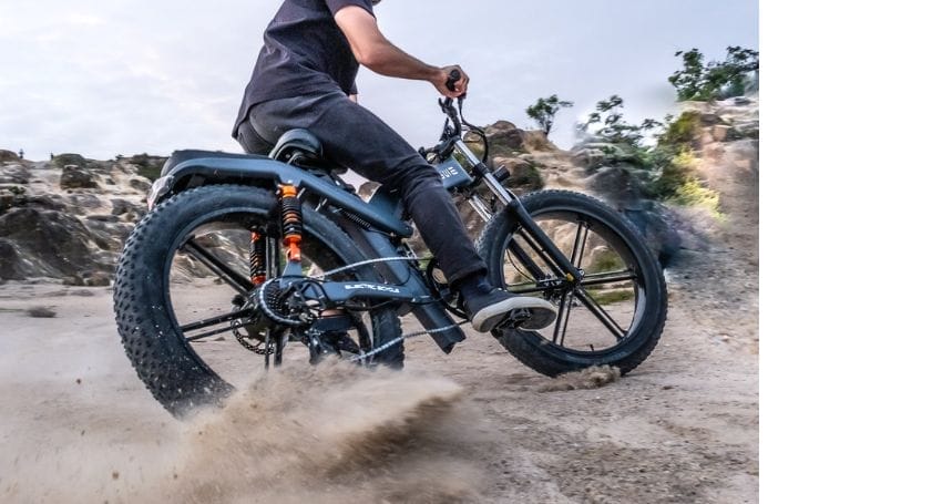 A man revolutionizes urban commuting by riding an electric bike through the sand.