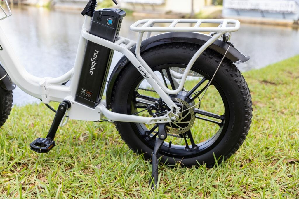 A white electric bike parked on the grass next to a body of water.