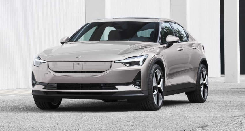 A silver electric sedan parked in front of a white industrial building, ideal for trend-conscious individuals.