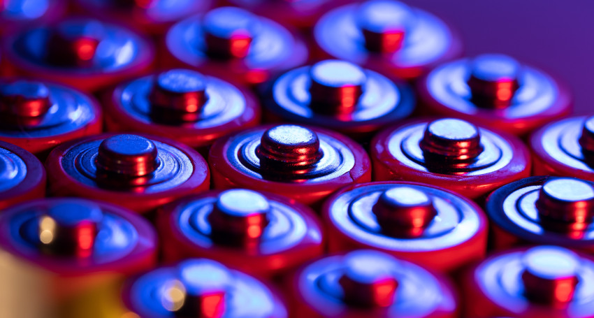 Close-up view of several rows of lithium-ion batteries with red and blue lighting.