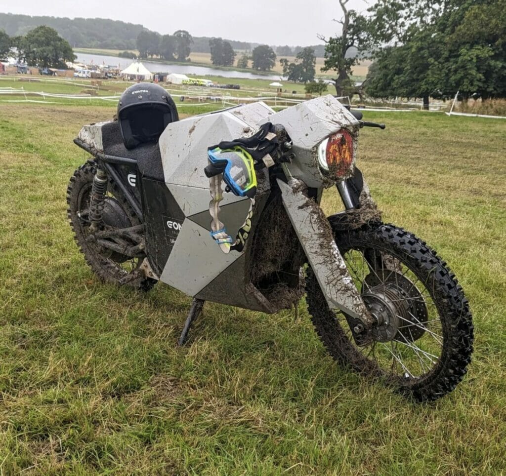 A motorcycle parked in a field near a lake.