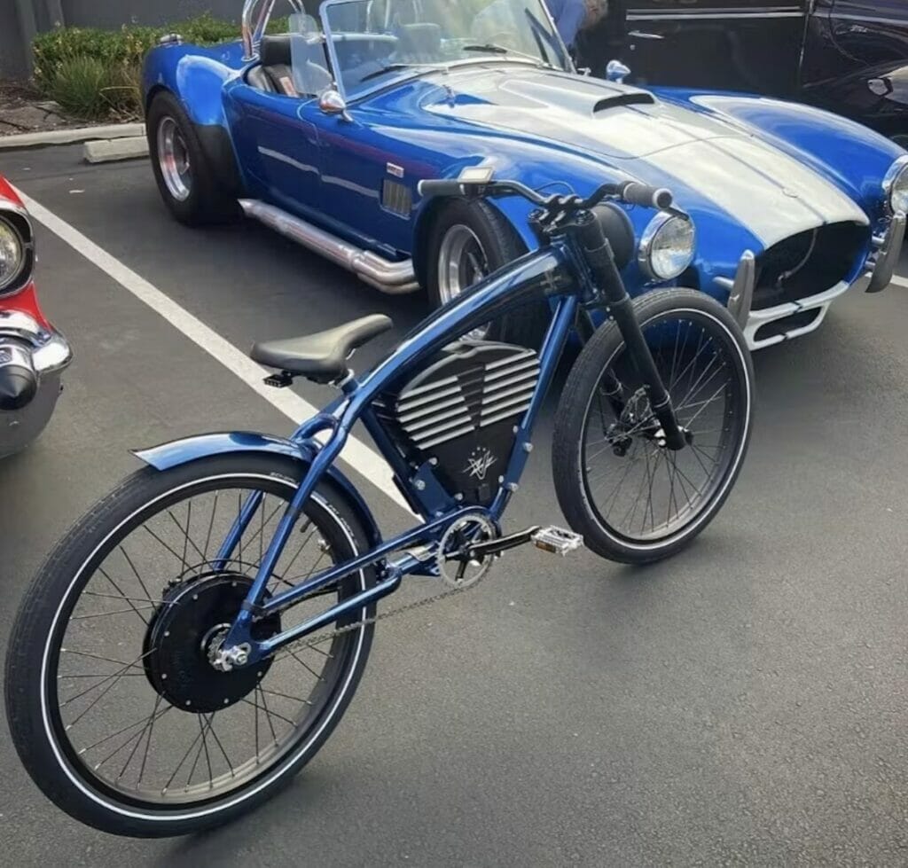 A high-quality vintage blue bike parked next to a classic car.