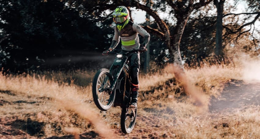 A person riding a mountain bike on a dirt trail made by Talaria Electric Motorcycles.