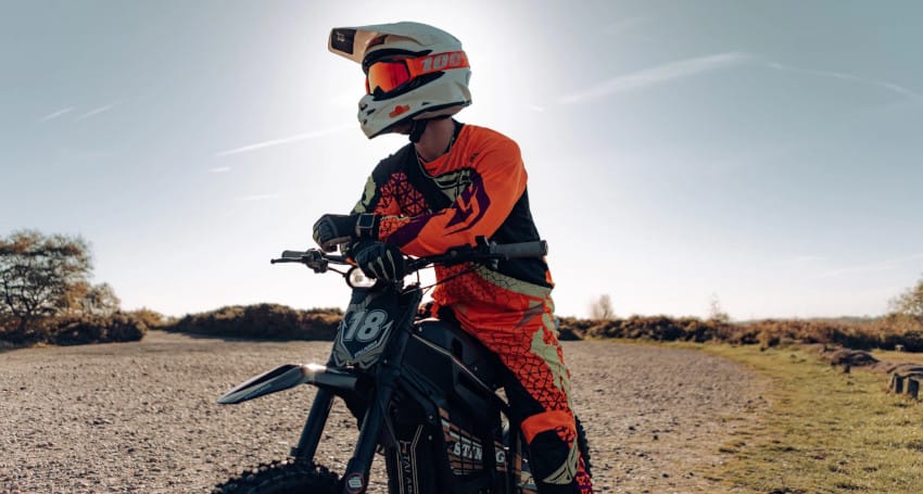 A person riding a dirt bike made by Talaria Electric Motorcycles on a dirt road.