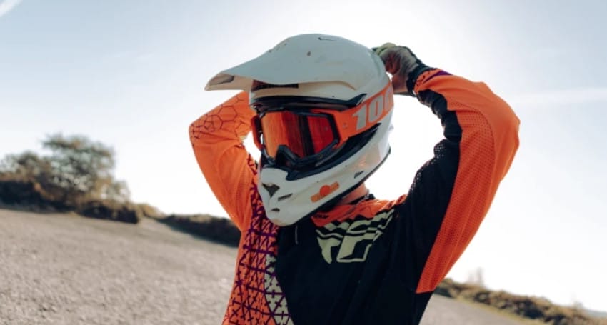 A person wearing a orange and black motorcycle helmet.