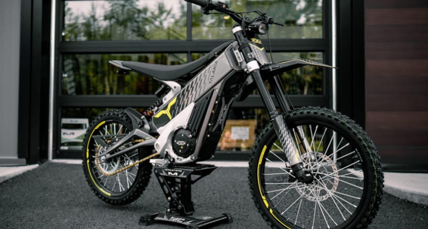 A dirt bike parked in front of the building where Talaria Electric Motorcycles are made.