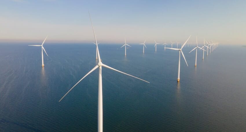 An aerial view of wind turbines in the ocean demonstrating sustainability.