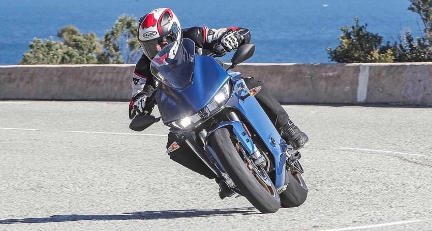 A person speeding on an electric blue Zero SR/S motorcycle on a road.