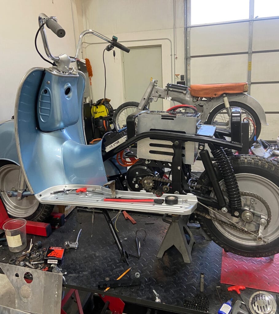 A scooter is being worked on in a garage for moto design.