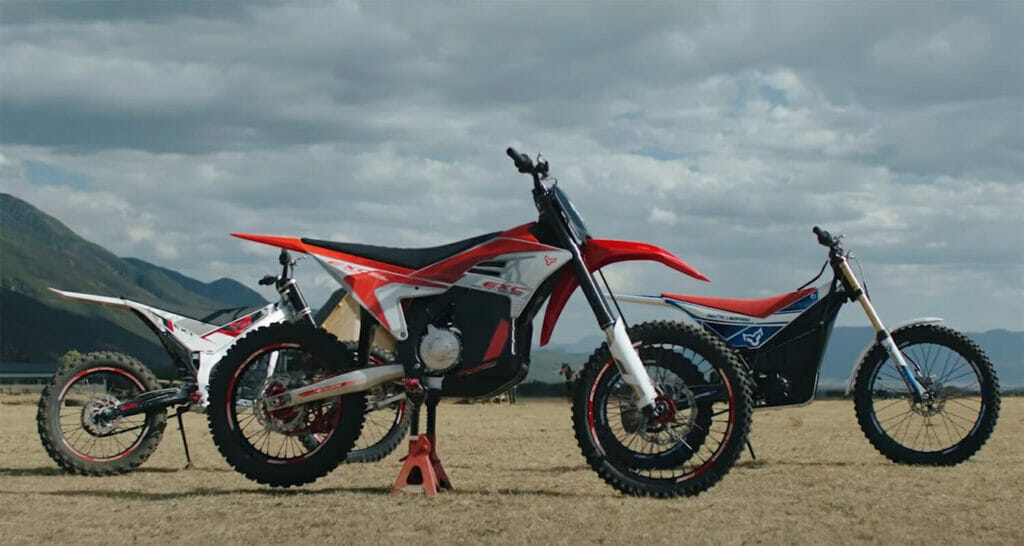 Arctic Leopard announces the unveiling of their new electric offroad models with three dirt bikes parked in a field with mountains in the background.