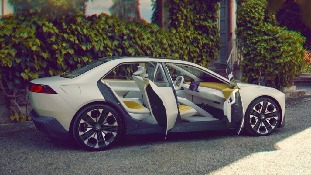 A futuristic BMW Vision Neue Klasse Concept car is parked on the side of a street, showcasing its minimalist design and giant head-up display.