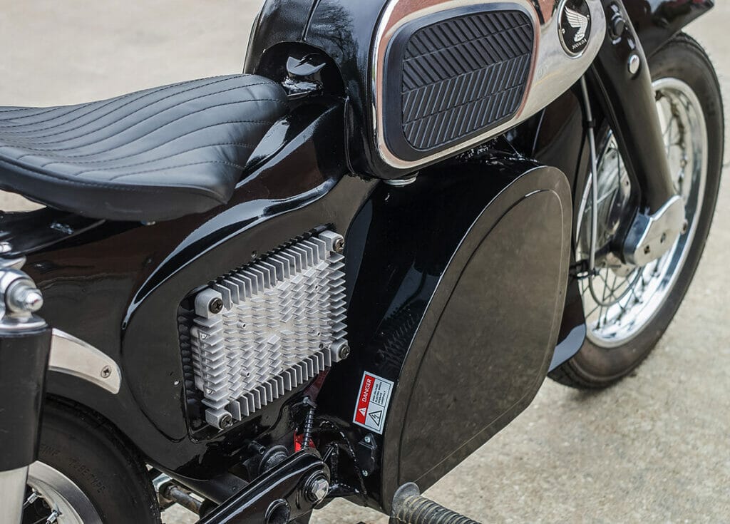 A 1967 Honda CA160 Dream motorcycle transformed into a silent beauty with a seamless electric conversion, now parked on the street.