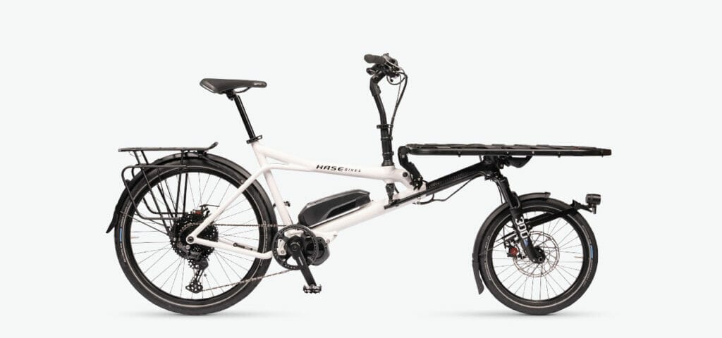 A white bicycle with a basket attached to it. Keywords: white, bicycle