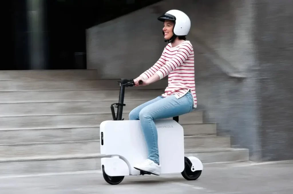 A woman riding a white scooter.