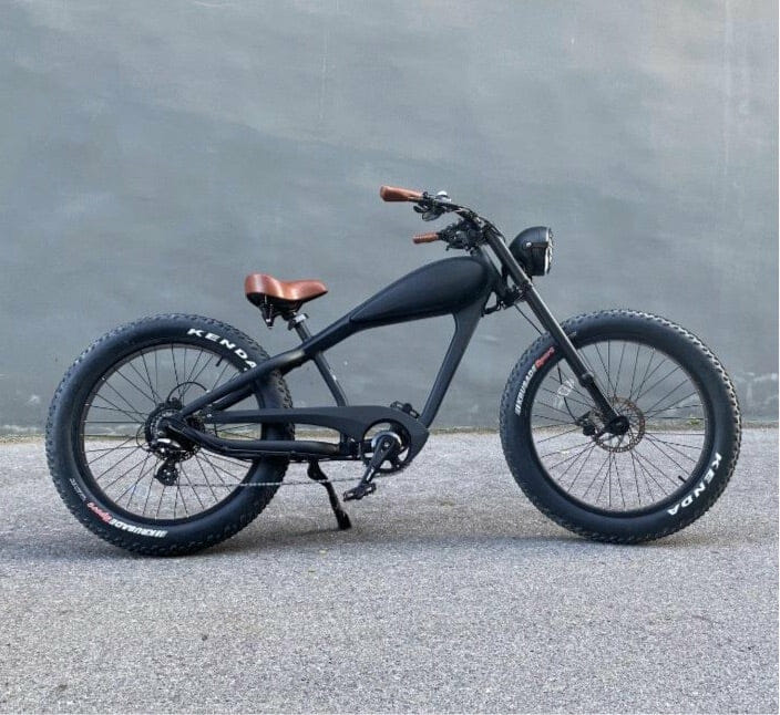 A black electric bike parked in front of a gray wall.