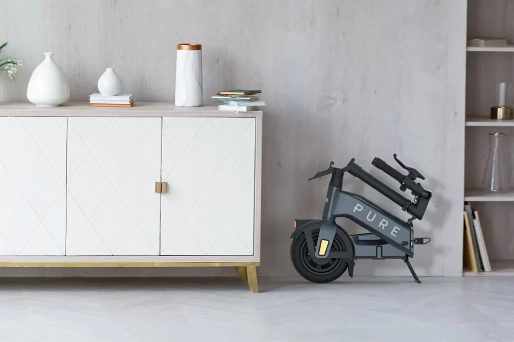An electric scooter in front of a white dresser.