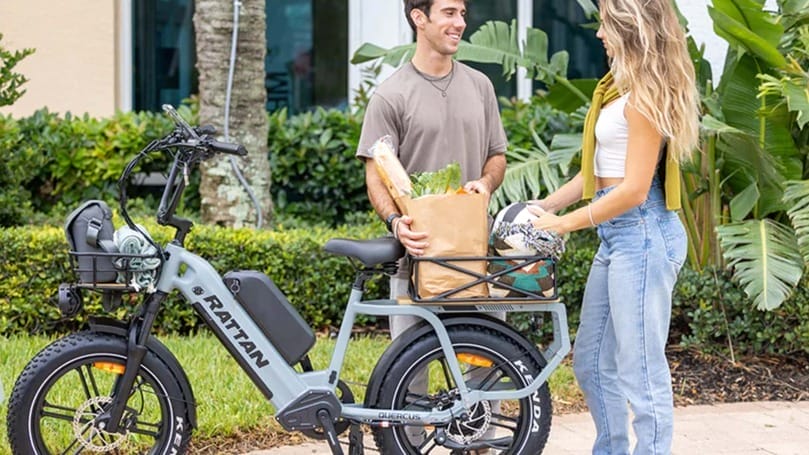 A man and woman standing next to a Quercus E-Bike with groceries on it.