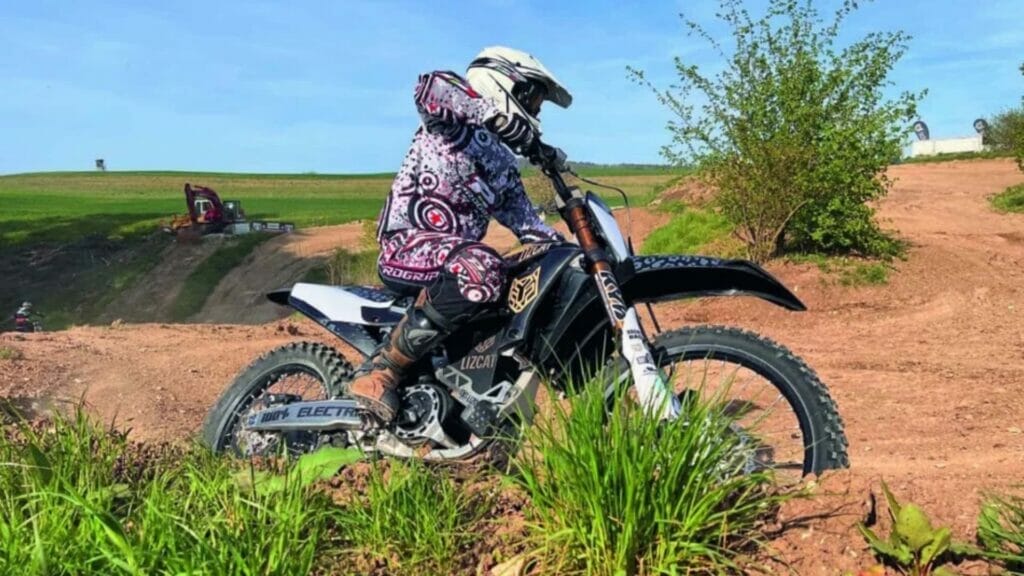 A person riding a dirt bike on an auto draft track.