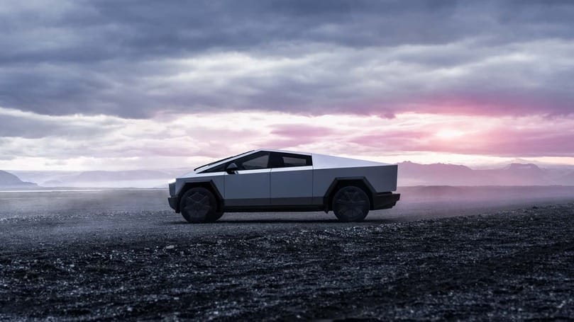 A white Tesla Cybertruck is driving on a deserted road.